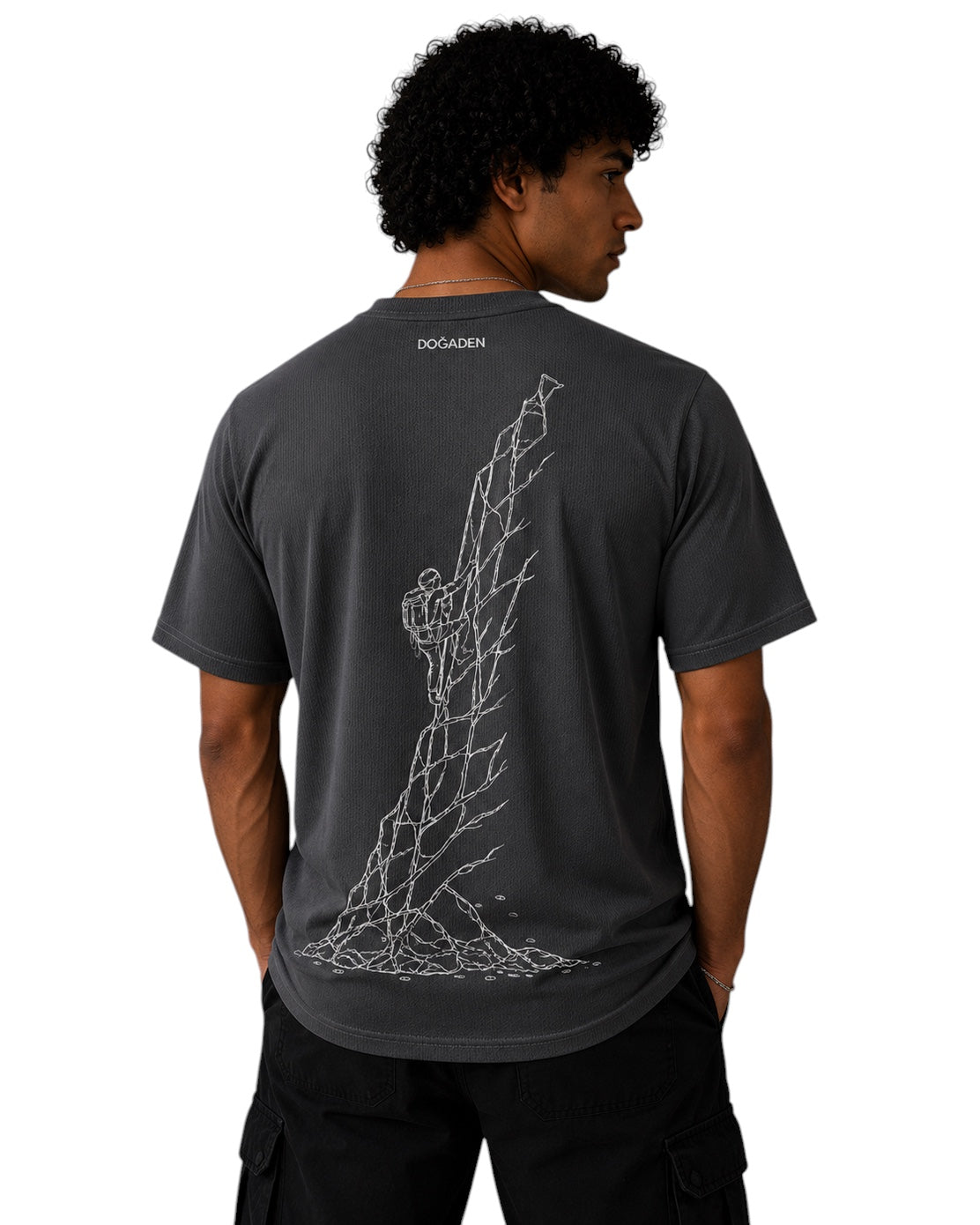 ArvoCulture marka, koyu gri, pamuklu t-shirt. Sırtta tırmanan bir figür ve taşları tasvir eden beyaz çizim baskısı. Erkek model üzerinde.