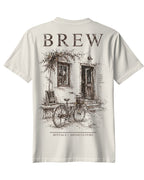 ArvoCulture marka, krem rengi, pamuklu, oversize tişört. Önünde bisiklet ve eski bir bina çizimi, üzerinde "BREW" yazısı.